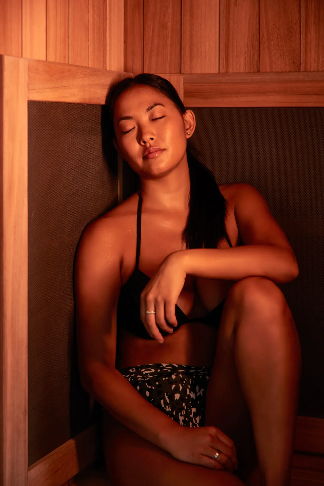 Guest resting in a cedar sauna under warm red light