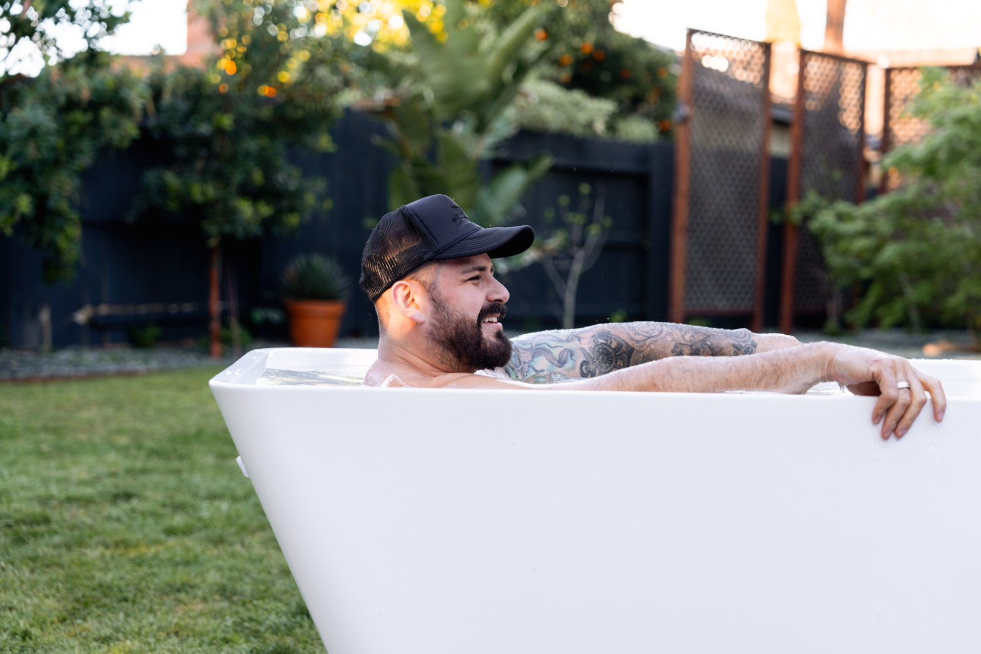 Smiling guest sitting in a cold plunge tub outdoors